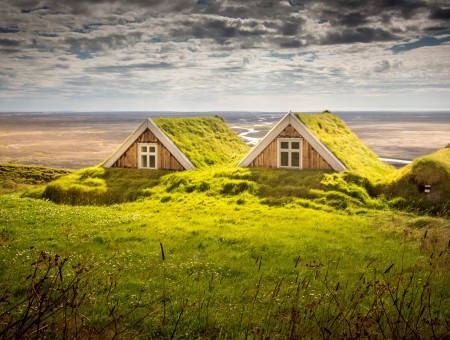House Covered In Green Moss Near Sand And Clouds