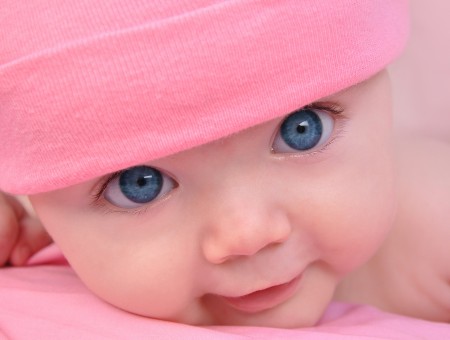 Baby In Pink Knit Cap Lying On Pink Textile