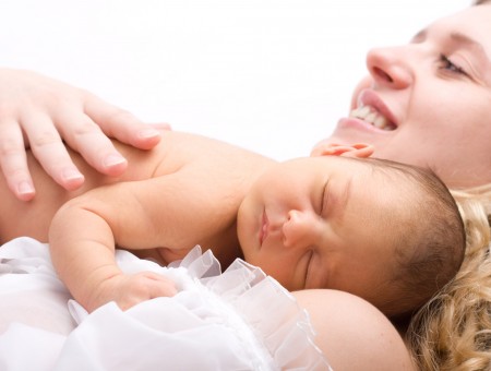 Woman Holding Nude Sleeping Baby Smiling