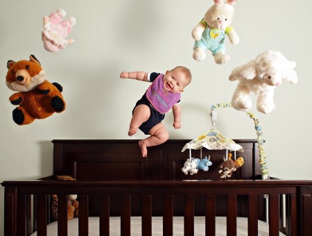 Smiling Baby Jumping Over Brown Wooden Crib