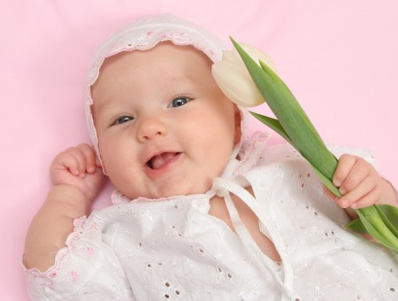 Baby In White Keyhole Long Sleeved Dress Holding White Tulip