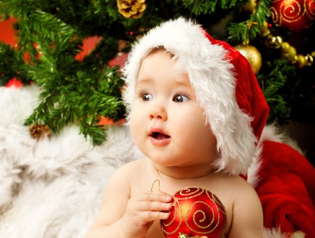 Topless Baby In Red Santa Hat Holding Gold And Red Christmas Bauble