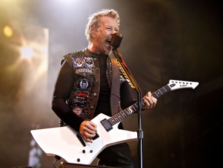 Man In Black Long Sleeve Shirt Holding White Electric Guitar Standing Behind Black Microphone