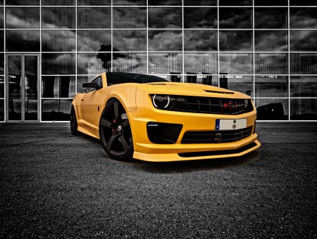 Yellow Chevrolet Coupe On Gray Rolled Asphalt Road Against Dark Skies