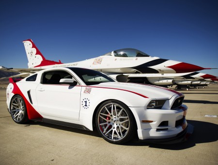 White And Red Jet Beside White And Red 2 Door Luxury Car Parked Under Blue Sky