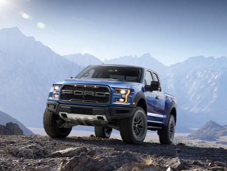 Blue Ford Pick-up Truck With Black Rims On Brown Dirt Road Under Blue Sunny Sky