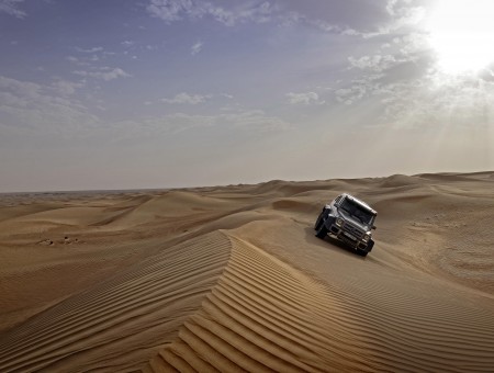 Gray Car Travelling On Desert Under Blue And White Sunny Sky