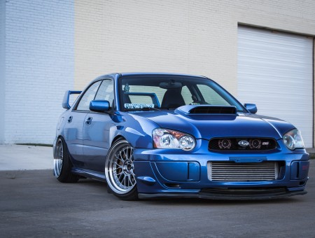 Blue Subaru Sedan With Blue Spoiler Parked In Front Of Garage