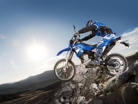 Man Riding Dirt Bike Jumping From Mountain Under Blue Sky During Daytime