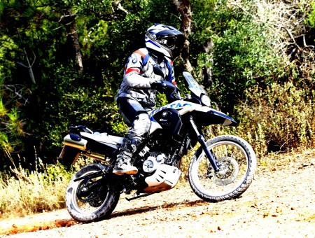 Person In Black And White Helmet Riding A Black And White Dirt Bike Near The Trees