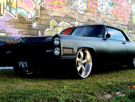 Black Muscle Car Parked Near Wall With Graffiti Art During Daytime