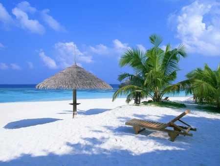 Brown Wooden Lounge Chair On White Sand Beside Beach Under Blue Sky And White Clouds
