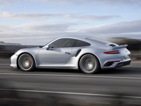 Gray Porsche 911 Speeding Across Asphalt Road During Daytime