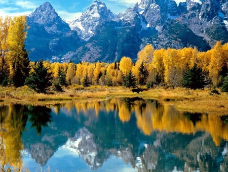 Grey Rocky Mountain Over Yellow Leaves Tree Close A Calmed Water Lake During Daytime
