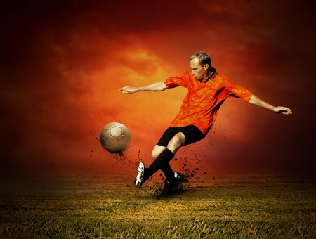 Soccer Player In Orange Jersey Kicks Soccer Ball On Grass Field