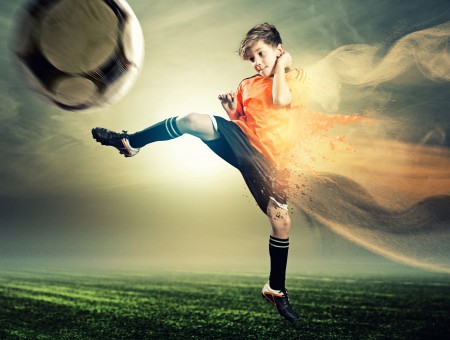Boy In Orange Shirt Kicking Black And White Soccer Ball During Daytime