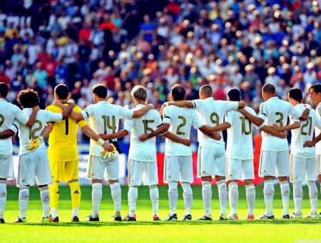 Men In White Outfits With Gold Numbers On The Back Standing In A Line With Their Arms Around Each Other