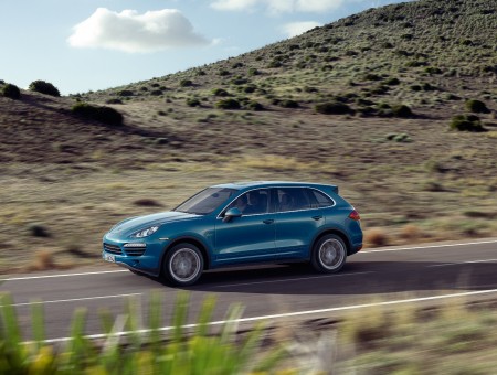 Blue Porsche Cayenne Driving On Country Road At Daytime