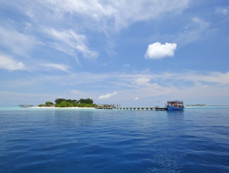 Boat Docked Near Islet Under White Clouds And Blue Sky During Daytime