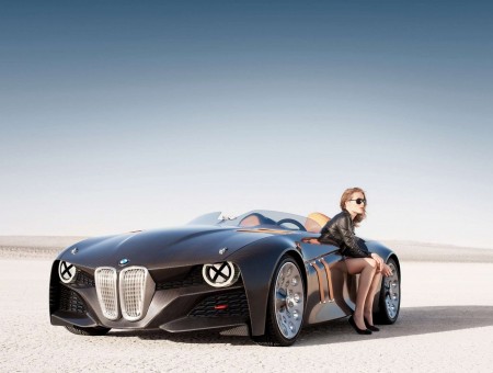 Black BMW Concept Car With Woman Wearing Black Leather Jacket Sitting On The Side During Daytime