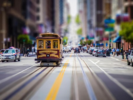 Tilt Shift Lens Photography Of Tram On Road Passing Other Cars During Daytime