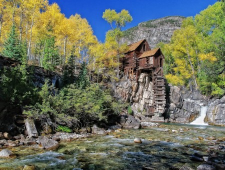 Green Trees Beside Brown Wooden House On Gray Rock Cliff