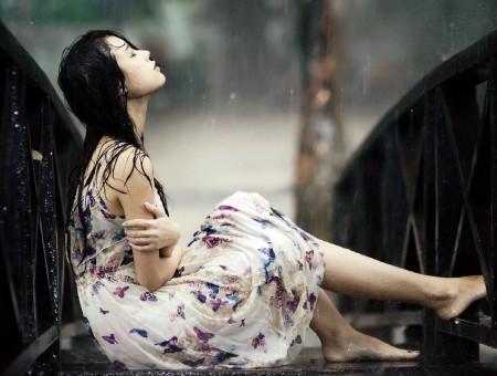 Woman Wearing White Purple And Blue Maxi Dress Between Brown Wooden Fence Getting Wet In The Rain
