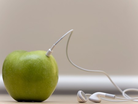 White And Gray Earbuds Plugged On Green Apple