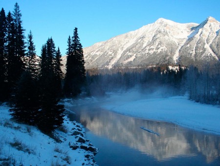 fog above river beside mountains in winter